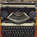 An Old Typewriter On A Desk Surrounded By Books Coffee And A Phone